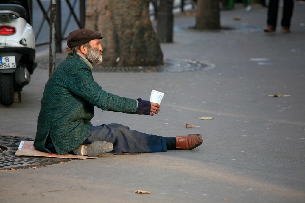 Homeless man on ground with change cup